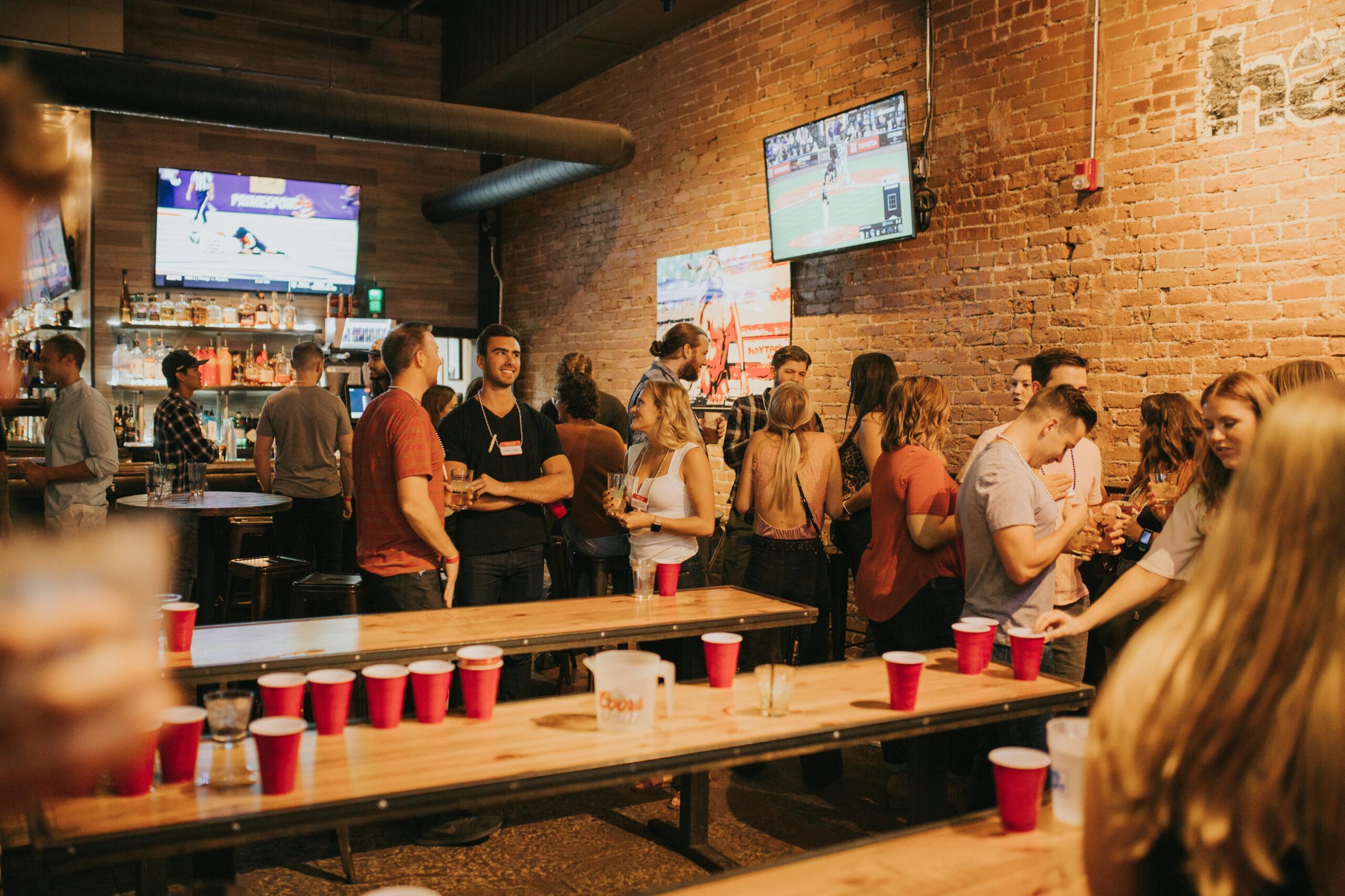 Energetic bar party with people socializing in Denver. Enjoyment and games in a lively pub atmosphere.